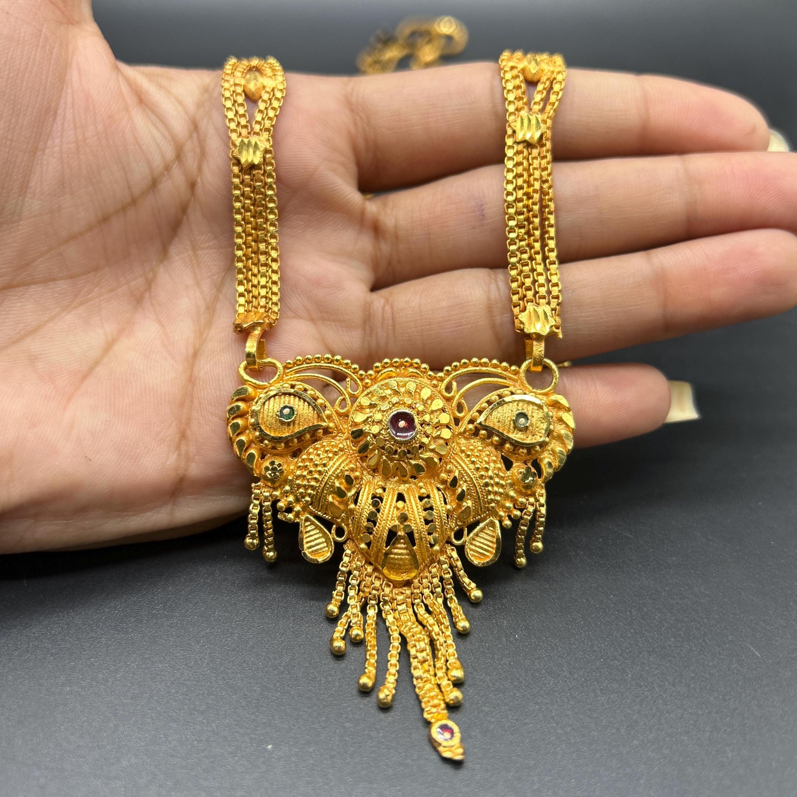 Gold-plated black beaded long mangalsutra, has a stylized centerpiece with textured details