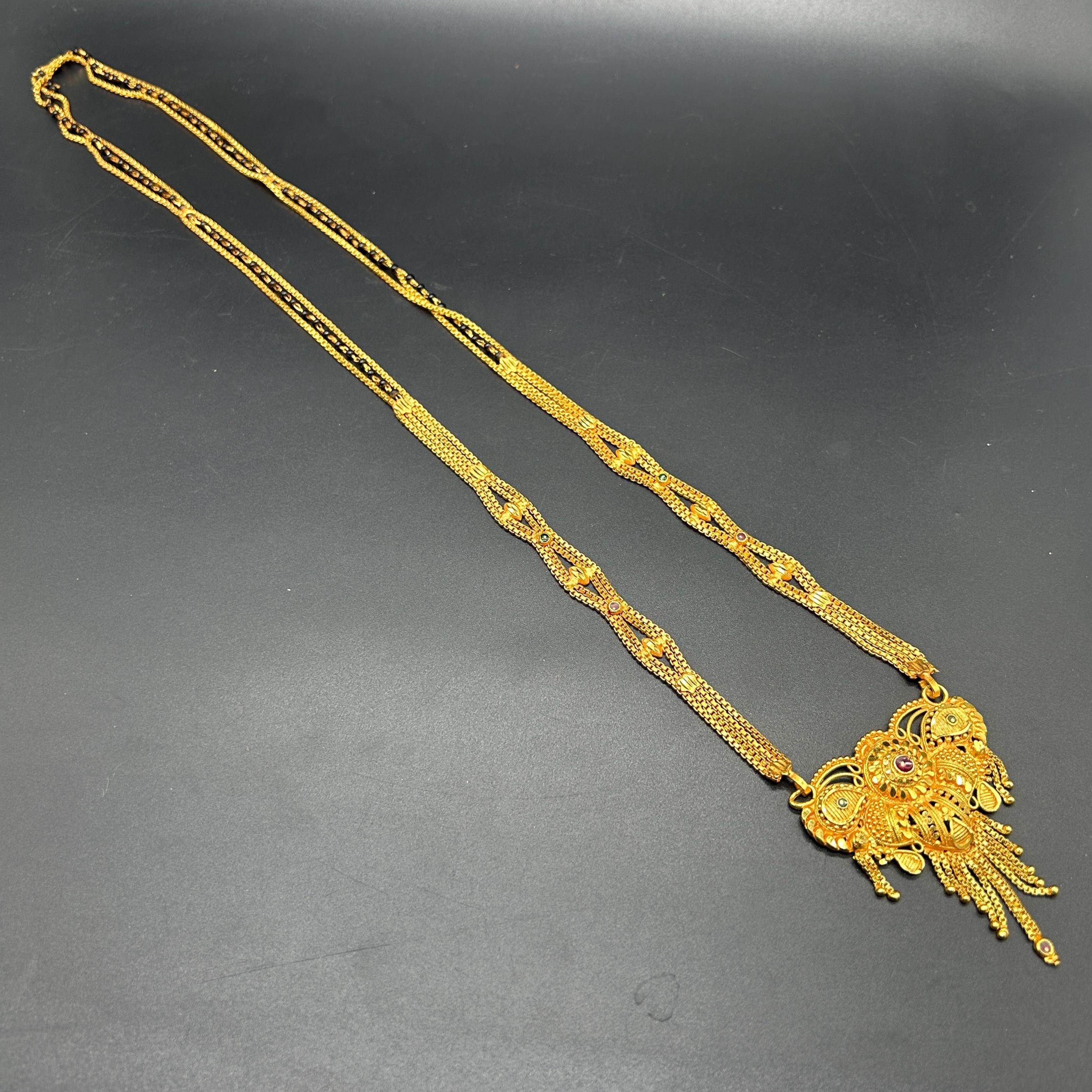 Gold-plated black beaded long mangalsutra, has a stylized centerpiece with textured details
