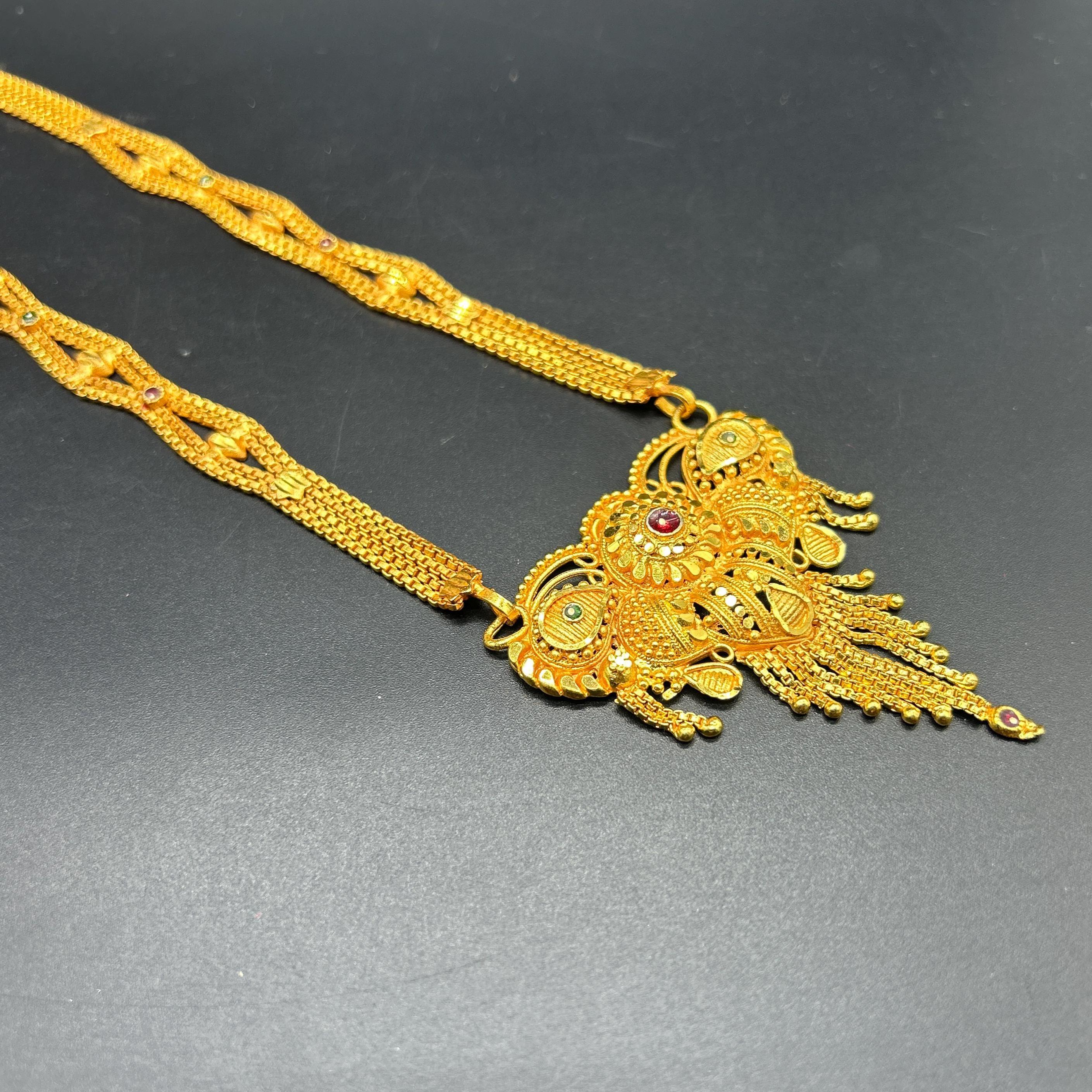 Gold-plated black beaded long mangalsutra, has a stylized centerpiece with textured details