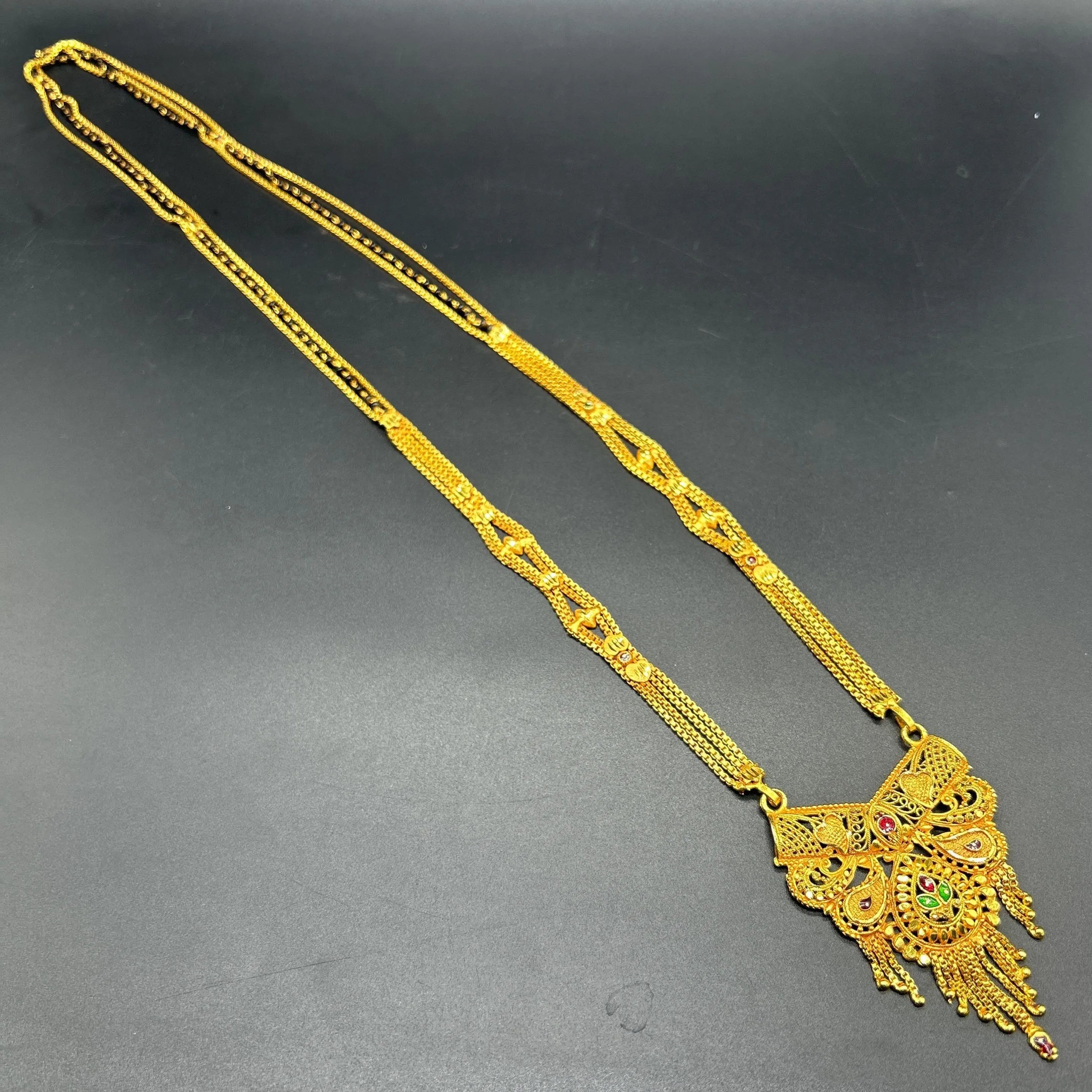 Gold-plated black beaded long mangalsutra, has a stylized centerpiece with textured details