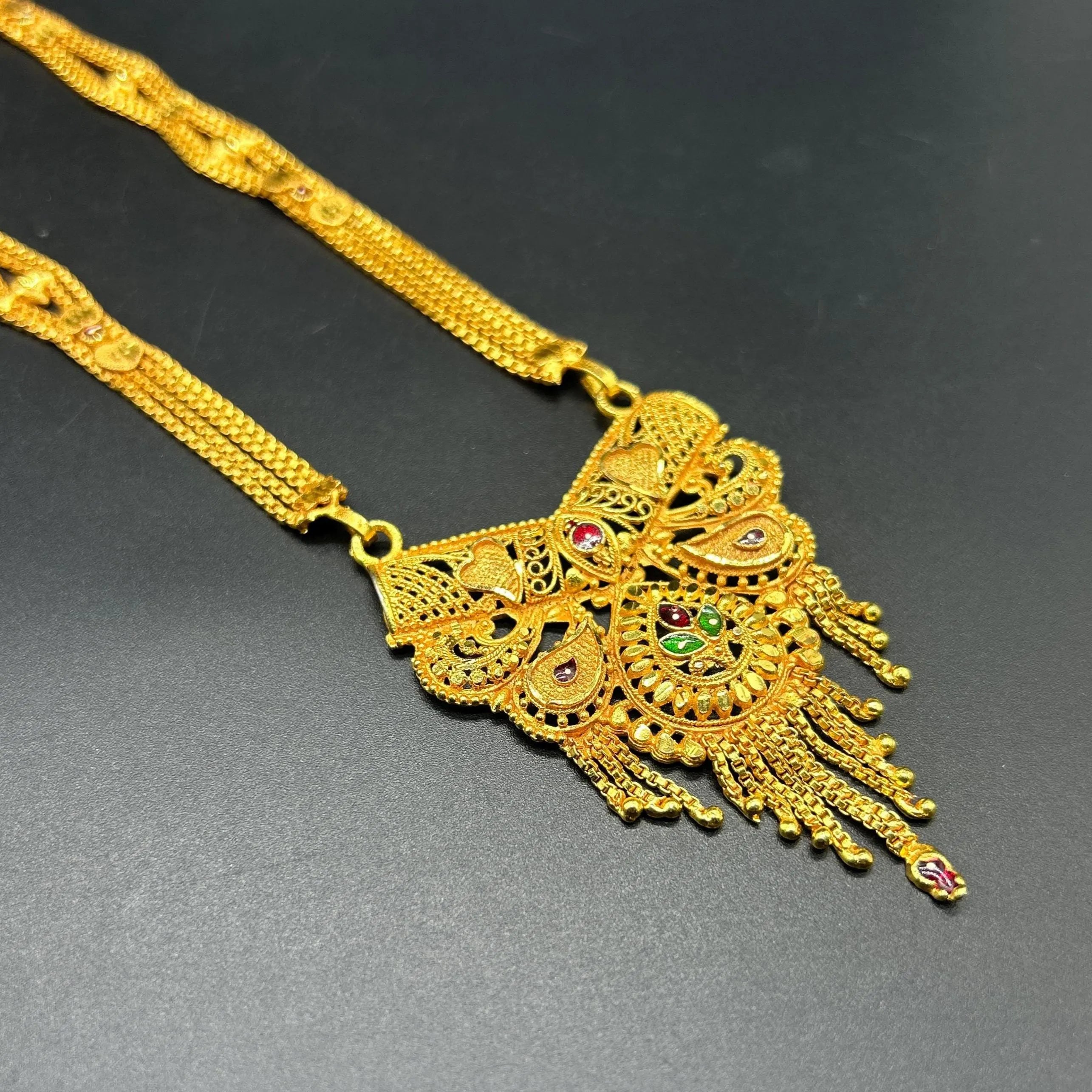 Gold-plated black beaded long mangalsutra, has a stylized centerpiece with textured details