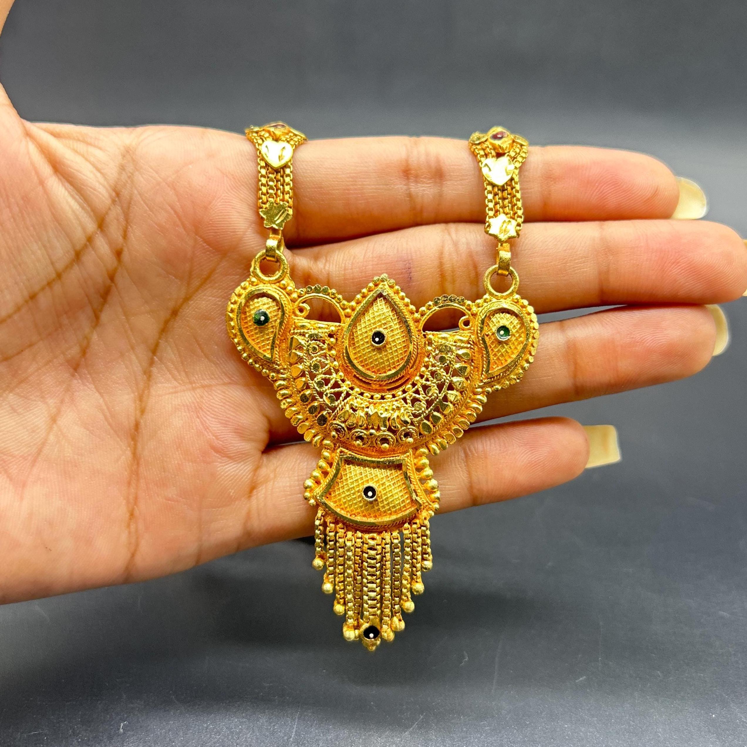 Gold-plated black beaded long mangalsutra, has a stylized centerpiece with textured details